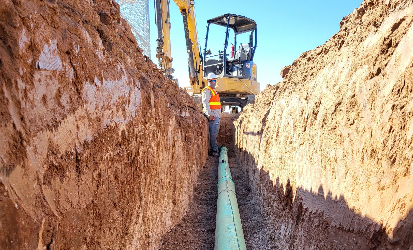 Mir Construction worker installing sewage pipe in trench